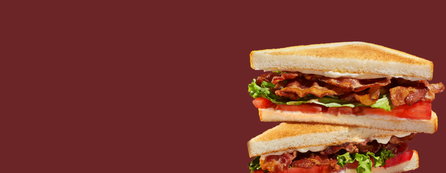 BLT sandwich stack on a dark red background